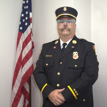Justin Carroll in uniform next to flag